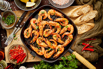 Image showing Tasty appetizing roasted shrimps prawns with spices on pan with ingredients on rusty background