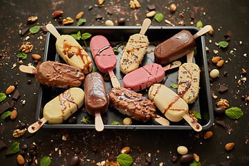 Image showing Set of delicious white and milk chocolate and strawberry ice cream on a stick served in metal tray