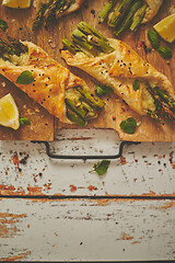 Image showing Baked green asparagus wrapped in puff pastry. Served on wooden board. With copy space