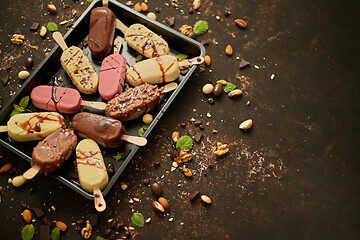 Image showing Set of delicious white and milk chocolate and strawberry ice cream on a stick served in metal tray