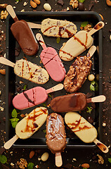 Image showing Assortment of various popsicle ice cream, white and dark chocolate, with almonds, rusty background