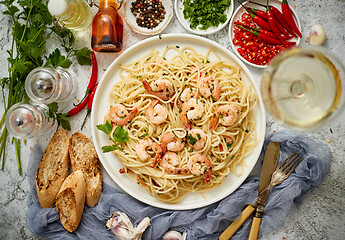 Image showing Spaghetti with shrimps on white ceramic plate and served with glass of white wine