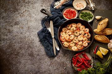 Image showing Grilled shrimps in cast iron grilling pan with fresh lemon, parsley, chili, garlic white wine sauce