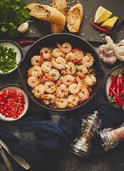 Image showing Fried baby Shrimps served on iron pan and fresh herbs and ingredients. Top view, flat lay