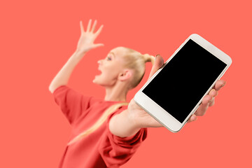 Image showing Portrait of a confident casual girl showing blank screen mobile phone isolated over coral background