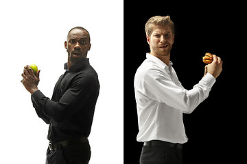 Image showing Men eating a hamburger and fruits on a black and white background