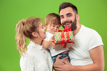 Image showing happy family with kid together and smiling at camera isolated on green