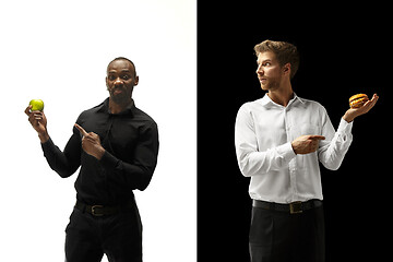 Image showing Men eating a hamburger and fruits on a black and white background