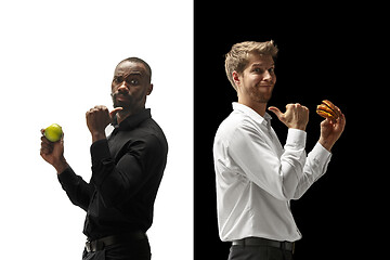 Image showing Men eating a hamburger and fruits on a black and white background