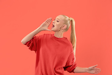 Image showing Isolated on coral young casual woman shouting at studio