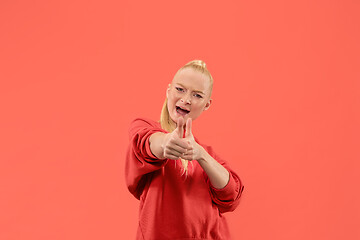 Image showing The happy business woman standing and smiling against coral background.