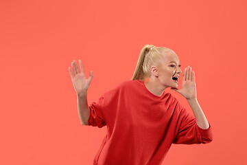 Image showing Isolated on coral young casual woman shouting at studio