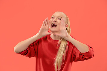 Image showing Isolated on coral young casual woman shouting at studio