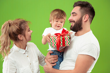 Image showing happy family with kid together and smiling at camera isolated on green