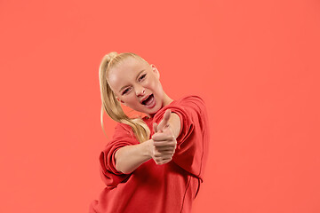 Image showing The happy business woman standing and smiling against coral background.