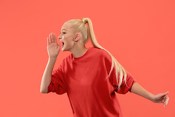 Image showing Isolated on coral young casual woman shouting at studio