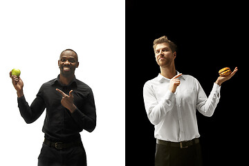 Image showing Men eating a hamburger and fruits on a black and white background