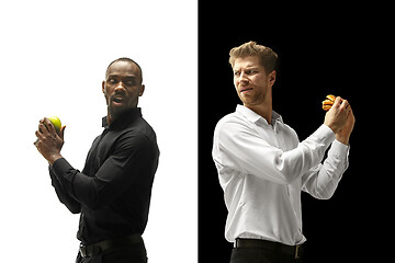 Image showing Men eating a hamburger and fruits on a black and white background