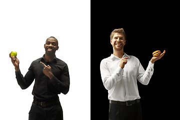 Image showing Men eating a hamburger and fruits on a black and white background