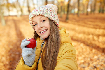 Image showing happy girl with apple taking selfie at autumn park