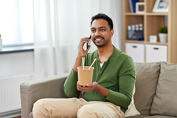 Image showing smiling indian man eating takeaway food at home