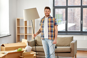 Image showing happy man with floor lamp moving to new home