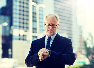 Image showing senior businessman checking time on his wristwatch