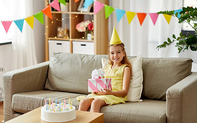 Image showing happy girl in party hat with birthday gift at home