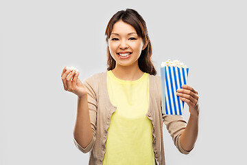 Image showing smiling asian woman eating popcorn