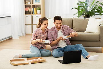 Image showing happy couple with laptop eating pizza at home