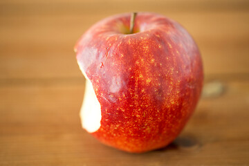 Image showing ripe red bitten apple on wooden table