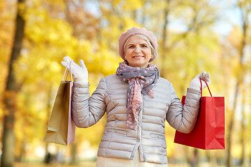 Image showing senior woman with shopping bags at autumn park