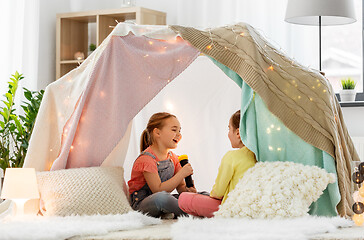 Image showing girls playing with torch in kids tent at home