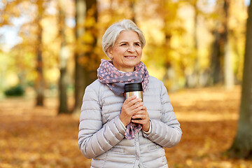 Image showing old woman with hot drink in tumbler at autumn park