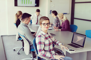 Image showing young business woman at office working on laptop with team on me