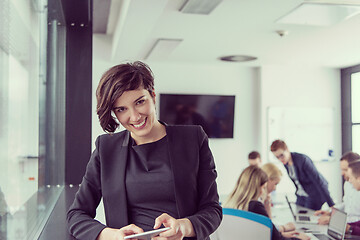 Image showing Elegant Woman Using Mobile Phone by window in office building