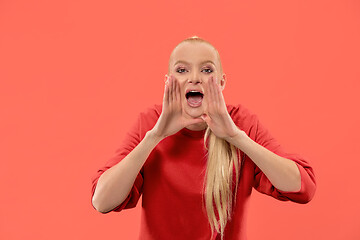 Image showing Isolated on coral young casual woman shouting at studio