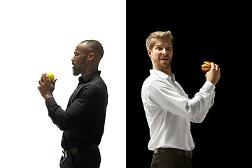 Image showing Men eating a hamburger and fruits on a black and white background