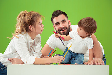 Image showing happy family with kid together and smiling at camera isolated on green