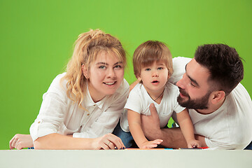 Image showing happy family with kid together and smiling at camera isolated on green