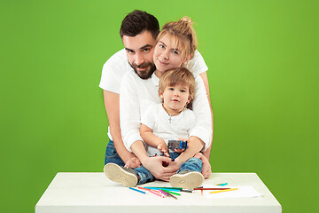 Image showing happy family with kid together and smiling at camera isolated on green