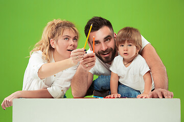 Image showing happy family with kid together and smiling at camera isolated on green