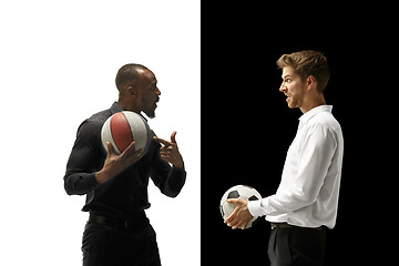 Image showing Portrait of a smiling men holding soccer and basketball ball isolated on a white and black background