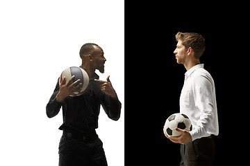 Image showing Portrait of a smiling men holding soccer and basketball ball isolated on a white and black background