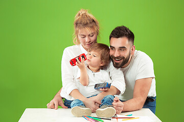 Image showing happy family with kid together and smiling at camera isolated on green