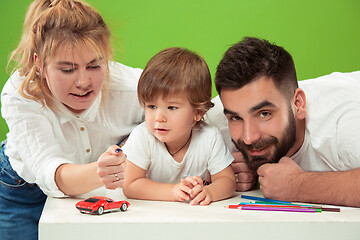 Image showing happy family with kid together and smiling at camera isolated on green