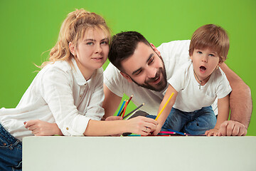 Image showing happy family with kid together and smiling at camera isolated on green