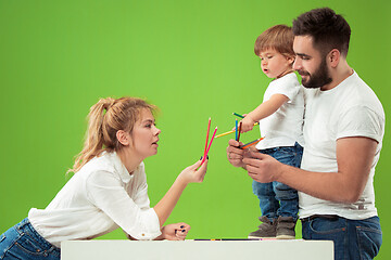 Image showing happy family with kid together and smiling at camera isolated on green