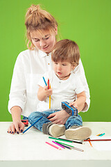 Image showing happy family with kid together and smiling at camera isolated on green