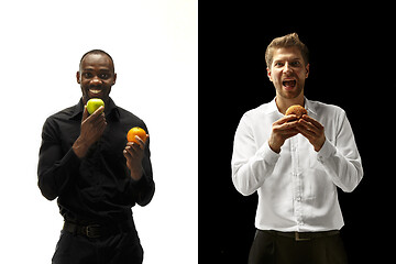 Image showing Men eating a hamburger and fruits on a black and white background